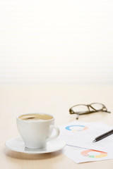 Office workplace with coffee, supplies and reports