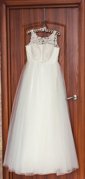 The perfect wedding dress with  full skirt on hanger in a room of  bride 