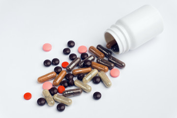 Different pills and capsules scattered on a white background.