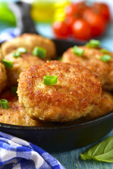 Chicken cutlests in a skillet.