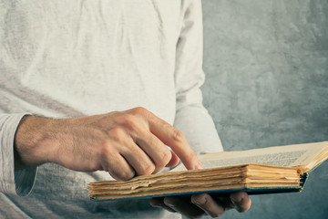 Man reading old book with torn pages