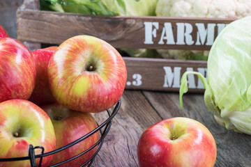 Farm organic apples in a basket and cabbage in farmers crates.