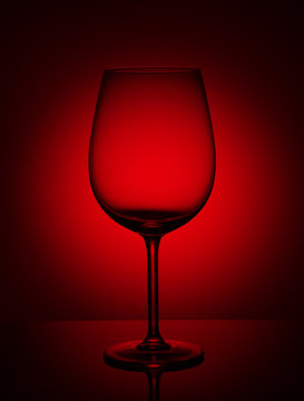 Empty wine glass on a red background.