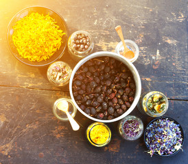 dry rose hips, herbs and flower petals in glass jars on the background of old wooden planks in the sunshine. selective focus. concept of aromatherapy, homeopathy, alternative medicine. square photo