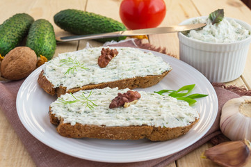 Nutritious sandwich with cottage cheese paste on rye bread on a white plate.
