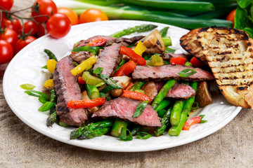 Grilled steak with stir-fried vegetables on plate.