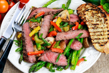 Grilled steak with stir-fried vegetables on plate.