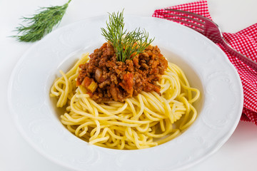 Spaghetti bolognese on white plate on white table.