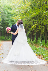 Fototapeta na wymiar Handsome brunette groom kissing beautiful bride in wedding dress 