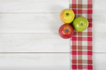 Apples placed on red checkered kitchen tablecloth. Top view.