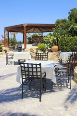Tables and iron chairs on terrace in garden, Crete, Greece
