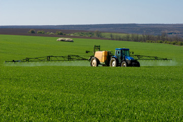 Tractor spraying pesticide in a field of wheat