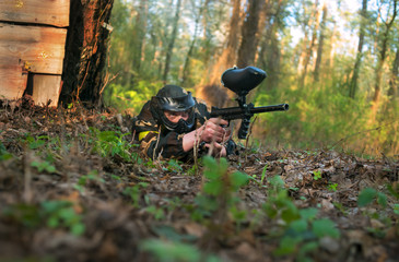 Man in a protective mask with a gun to play paintball in the woods in summer
