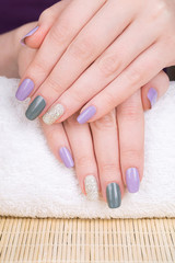 Manicure - Beauty treatment photo of nice manicured woman fingernails. Very nice feminine nail art with nice purple,silver and grayish nail polish.