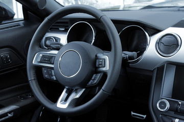 Control buttons on steering wheel inside leather car interior 