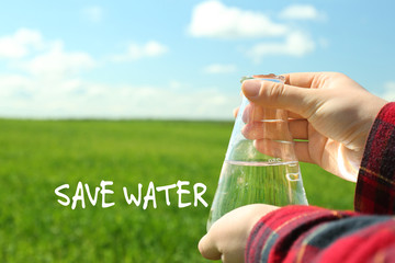 Female hands with flask and Save Water text on natural background