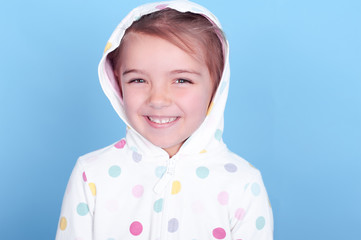 Laughing child girl 3-4 year old wearing hoodie with polka dots pattern over blue. Childhood. Positive emotions. Cheerful. Happiness. 