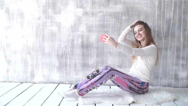 Happy teen girl listening to the music and chatting by smart phone taking selfies