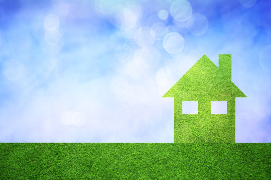 Eco green house concept copy space background with grass texture and blurred blue sky. Friendly living in eco green modern home.