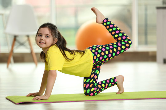 Little cute girl practicing yoga pose on a mat indoor