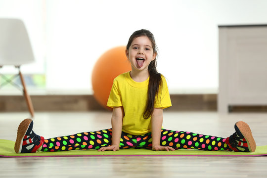 Little Funny Girl Sitting In The Splits On A Mat Indoor