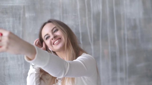 Happy teen girl listening to the music and chatting by smart phone taking selfies
