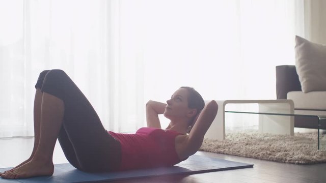 Young Woman Doing Stretching and Fitness in Living Room at Home. Shot on RED Cinema Camera.