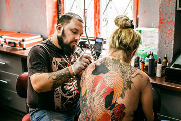 the process of creating a tattoo on the back of a girl