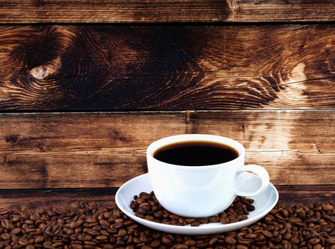 Cup of coffee with grains on wooden background.Copy space for your text.