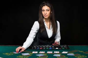 The beautiful girl, dealer, behind a table for poker