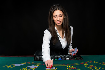 The beautiful girl, dealer, behind a table for poker
