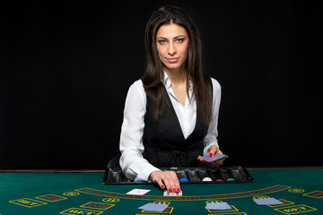 The beautiful girl, dealer, behind a table for poker