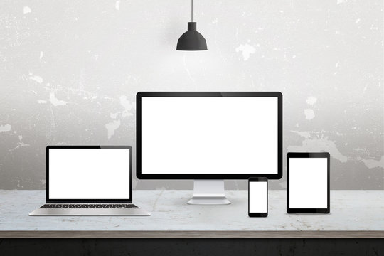 Devices with isolated white display for responsive web promotion. Computer, laptop, tablet, smart phone on desk.