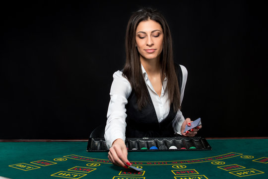 The beautiful girl, dealer, behind a table for poker