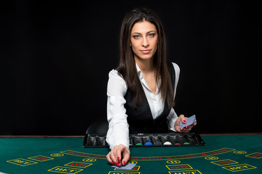The beautiful girl, dealer, behind a table for poker