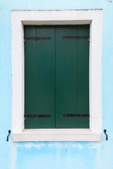 Obraz na płótnie Canvas Old window with dark green shutters on light blue wall