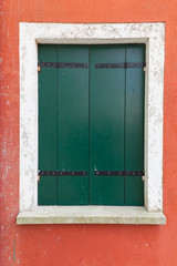 Fototapeta na wymiar Old window with green shutters on red wall