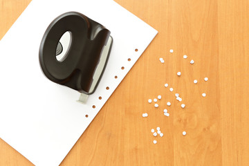 Hole puncher with paper on the office table, paper with holes