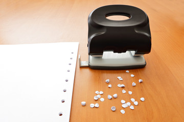 Hole puncher with paper and confetti on the office table