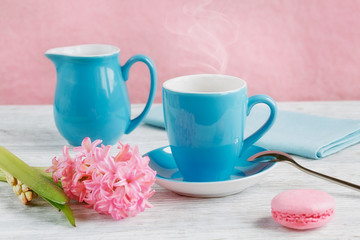 Fototapeta na wymiar Cup of black coffee, pink flowers and french macaroons