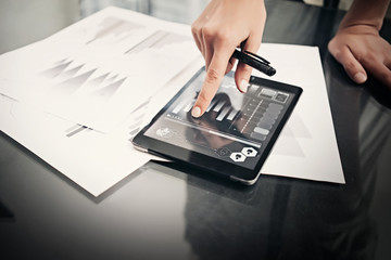 Picture woman working market reports modern tablet and touching screen with worldwide stock exchange icons. Documents for sign on the table. Horizontal. Film effect