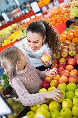 Fototapeta na wymiar Mother and smiling little daughter choosing seasonal fruits