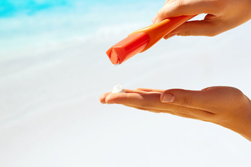 Bottle of suntan cream in female hands