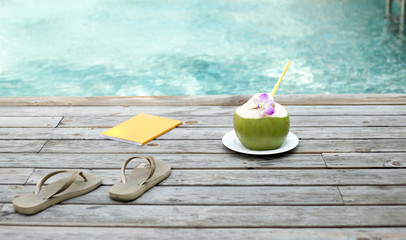 Coconut juice  with flower and book by the swimming