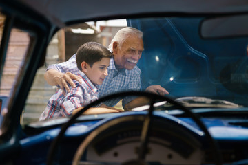 Boy With Grandpa Looking Car Engine Of Senior Man