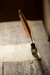 Ancient pen, inkpot and a paper on the table