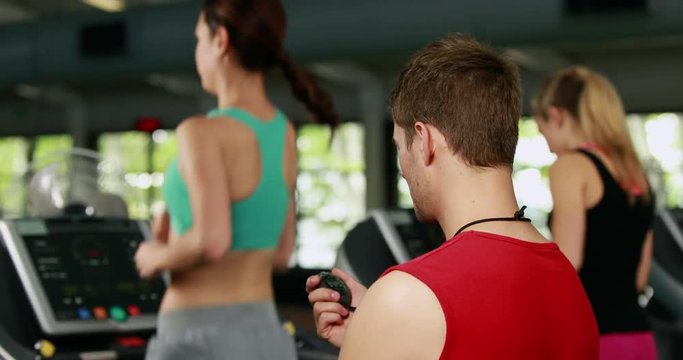 Male trainer checking treadmill performance