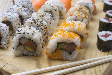 Different Sushi rolls,wasabi and ginger on a plate on wooden bac