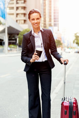 Business woman pulling suitcase walking in city