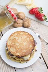 pancakes with banana, nuts and strawberry on wooden background